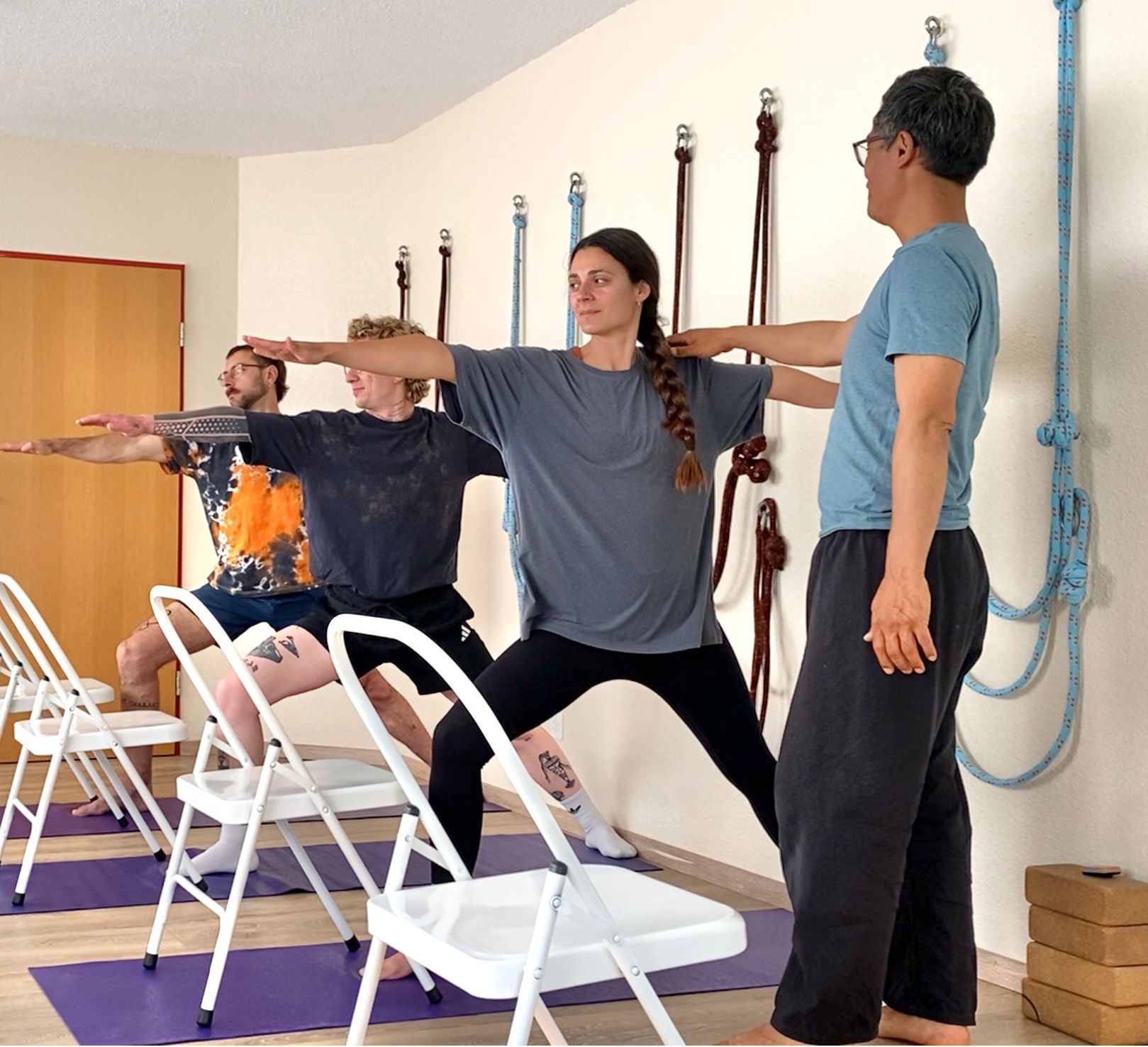 Iyengar Yoga St. Gallen — präzise Korrektur in Virabhadrasana II (Krieger II) während der Yogastunde